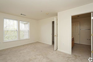 Carpeted bedroom with two windows door leading into bathroom
