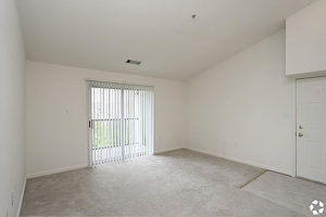 Carpeted living area with sliding glass door leading to balcony