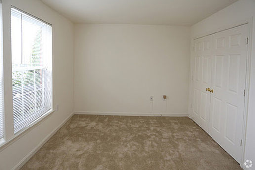 Carpeted bedroom with double door closet and window